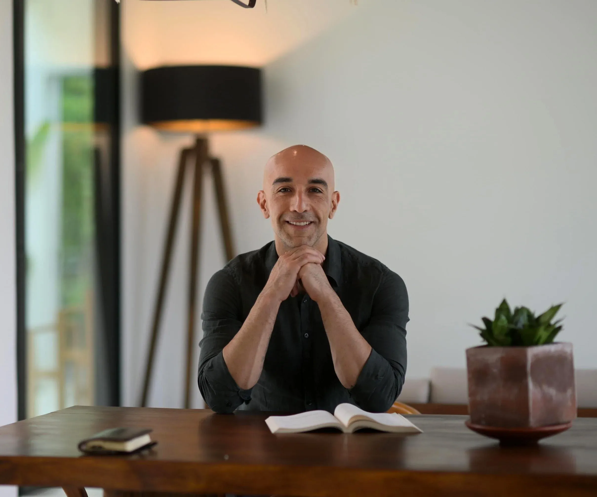 Mike McGregor leaning in at a wooden table, chin on his hands, an open book in front of him